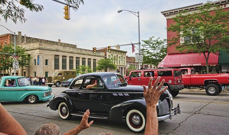 vintage cars mingle with traffic on a small town street