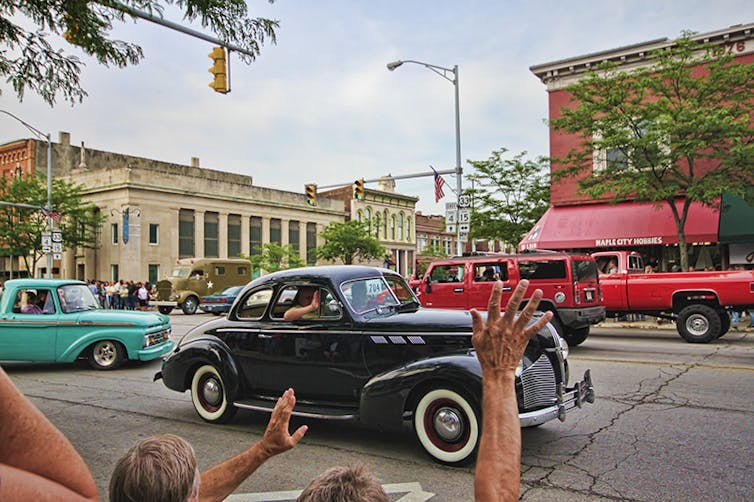 vintage cars mingle with traffic on a small town street